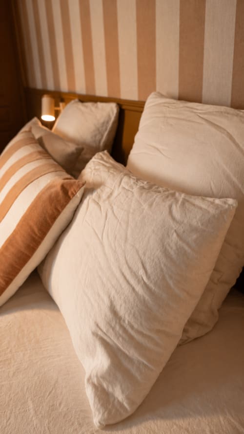 Literie à rayures crème et beige avec oreillers à La Maison 1903 B&B à Trévou-Tréguignec, France