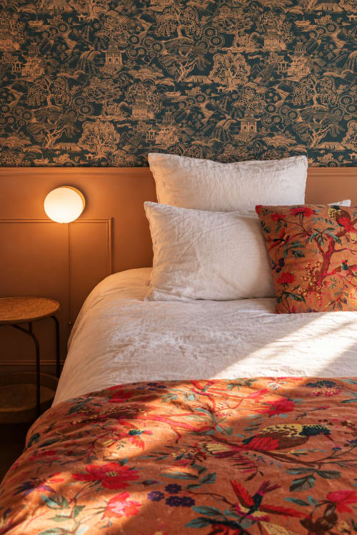 Sakura bedroom at La Maison 1903 with floral bedding, cream pillows, orange accent wall, and patterned headboard in