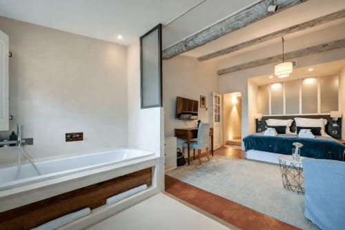 Suite Cezanne at Les Suites de Montigny: spacious bedroom with ensuite bath, wooden beams, blue velvet bed, and modern