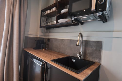 Modern kitchenette with black sink, wooden countertop, gas stove, and wall-mounted shelving at La Borda del Gato Rafa hotel