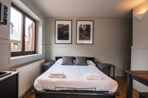 Deluxe Quadruple Room at La Borda del Gato Rafa in Vielha with queen bed, city view balcony, and framed artwork