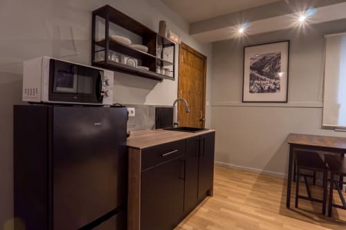 Modern kitchenette in Superior Quadruple Room at La Borda del Gato Rafa, Vielha, featuring dark cabinetry, refrigerator, and