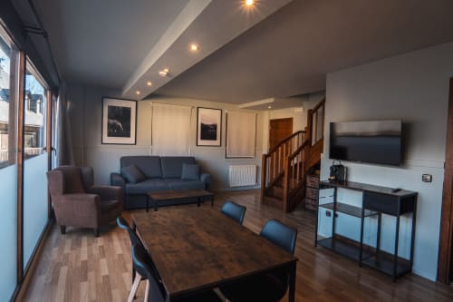 Superior Quadruple Room at La Borda del Gato Rafa in Vielha with dining table, sofa, TV, and city balcony views