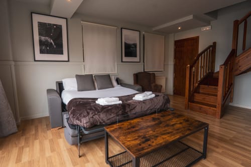 Superior Quadruple Room at La Borda del Gato Rafa in Vielha with sofa bed, wooden stairs, and city views