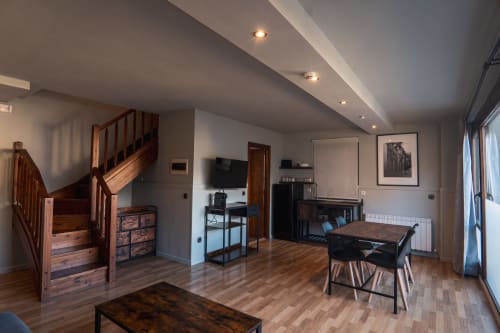 Modern Superior Quadruple Room at La Borda del Gato Rafa in Vielha with living area, dining table, and wooden staircase