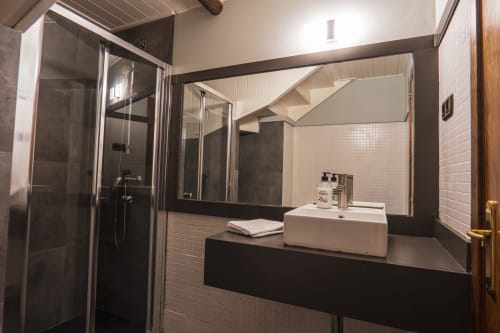 Modern bathroom in Deluxe Quadruple Room at La Borda del Gato Rafa, Vielha with walk-in shower, dark vanity, white sink, and