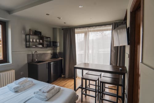 Modern hotel room at La Borda del Gato Rafa in Vielha with bed, kitchenette, dining area and city view windows