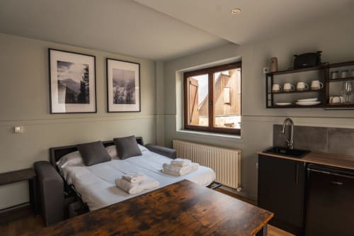 Deluxe Quadruple Room at La Borda del Gato Rafa in Vielha with sofa bed, wooden table, and kitchenette