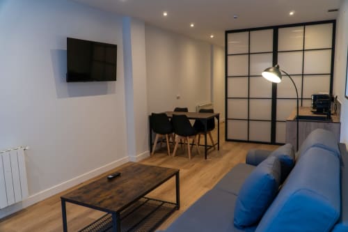 Premium Quadruple Room at La Borda del Gato Rafa in Vielha featuring blue sofa, dining area, and wall-mounted TV