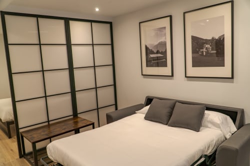 Premium Quadruple Room at La Borda del Gato Rafa in Vielha with bed, gray pillows, framed mountain photographs, and modern