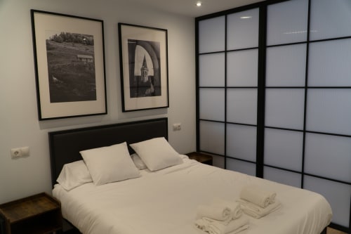 Premium Quadruple Room at La Borda del Gato Rafa hotel in Vielha with bed, black framed artwork, and modern wardrobe.