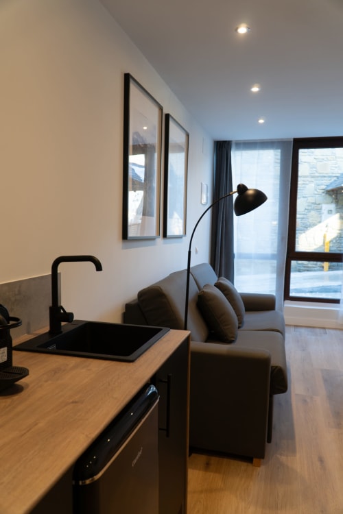 Modern hotel room at La Borda del Gato Rafa in Vielha with kitchenette, black lamp, and mountain views