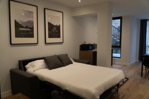 Premium Quadruple Room at La Borda del Gato Rafa in Vielha with sofa bed, mountain artwork, and balcony access