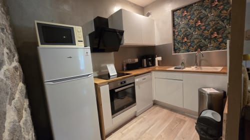 Cuisine moderne avec meubles et électroménagers blancs, appartement Le Mahé de la Bourdonnais, Manoir de la Bégaudière, Mont-Dol