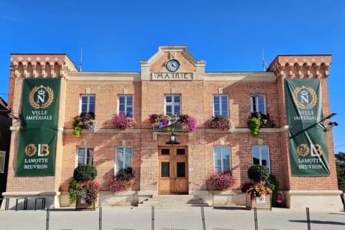 Bâtiment historique de la Mairie à Sennely, France, avec façade en briques rouges et jardinières fleuries aux fenêtres