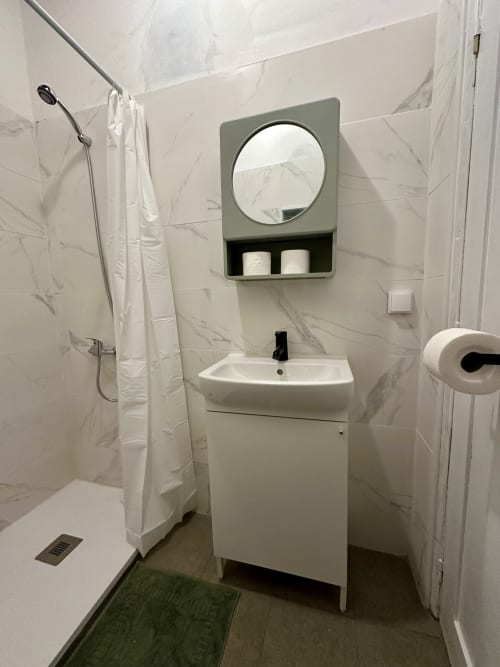 Banheiro moderno do apartamento Casa do Taxista nas Villas Simone Porto Santo com azulejos em mármore branco, pia com espelho redondo