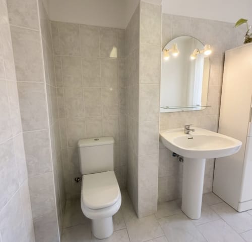 Banheiro moderno nas Villas Simone Porto Santo com vaso sanitário, pia de pedestal e espelho com iluminação