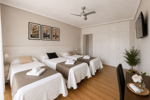 Habitación triple en Muro 13 El Mirador del Espolón de Logroño con tres camas, ropa de cama blanca, suelo de madera y vistas a la ciudad