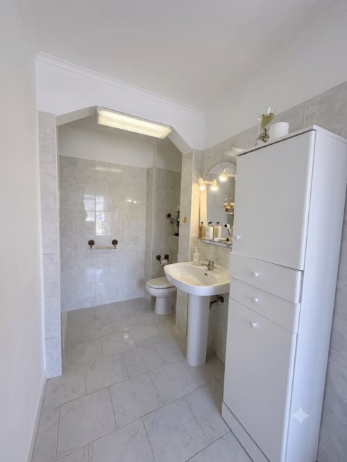 Banheiro moderno do Apartamento Family & Friends nas Villas Simone Porto Santo com chuveiro walk-in, pia pedestal e acabamentos brancos