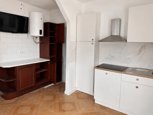 Cozinha de apartamento familiar nas Villas Simone Porto Santo com armários brancos, painel traseiro de mármore e bancadas de madeira