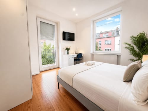 Chambre moderne chez Mattbnb Metz avec lit queen-size, bureau, TV et balcon vue sur la ville