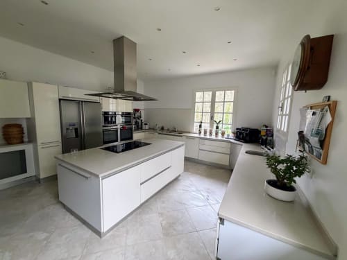 Modern white kitchen with island, stainless steel appliances, and natural light at Domaine de Bize in Mirepoix, France