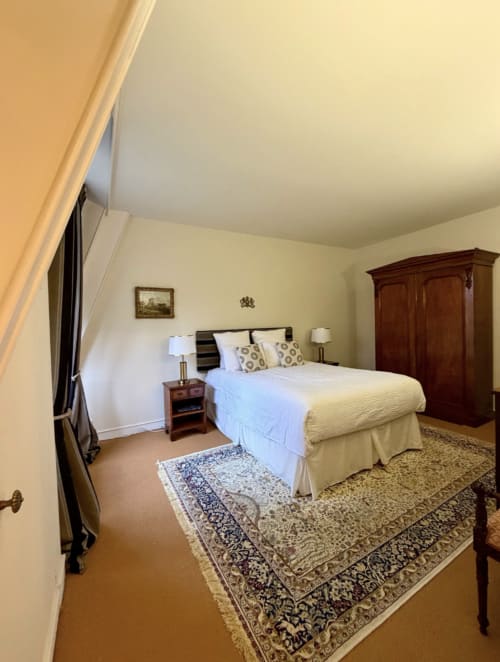 Elegantes Schlafzimmer im Schloss Domaine de Bize in Mirepoix mit Queen-Size-Bett, hölzernem Kleiderschrank und historischen Möbeln