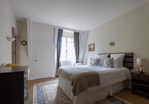 Elegantes Schlafzimmer im Domaine de Bize Mirepoix mit Queen-Bett, Holzmöbeln und Erkerfenster mit Blick auf die Gärten in Ariège