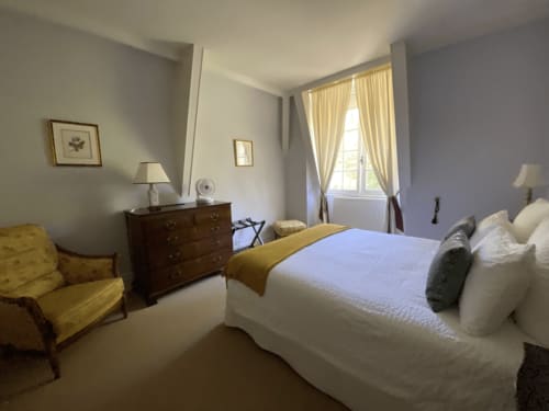 Elegant bedroom at Domaine de Bize manor in Mirepoix with queen bed, yellow armchair, and garden views