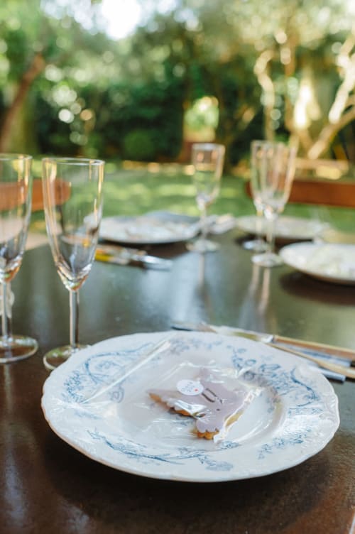 Élégante mise de table en terrasse à l'Auberge du Parc avec service bleu et blanc, verres à vin et verdure luxuriante