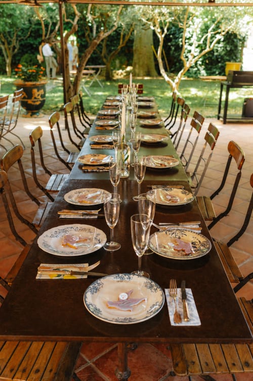 Table de salle à manger dressée pour un événement en plein air à l'Auberge du Parc à Correns avec des couverts élégants et des arbres