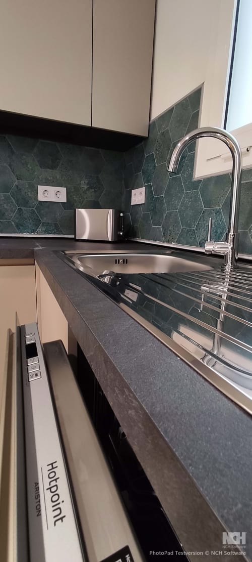 Modernes Spülbecken mit Chromarmatur, dunkelgrüne Hexagon-Fliesenwand und Edelstahlgeräte in Fly High
