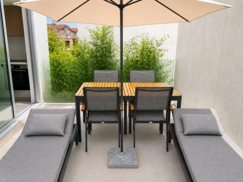 Terraza moderna en Sabarís con mesa de comedor, tumbonas, sombrilla y plantas verdes junto a Playa Ladeira