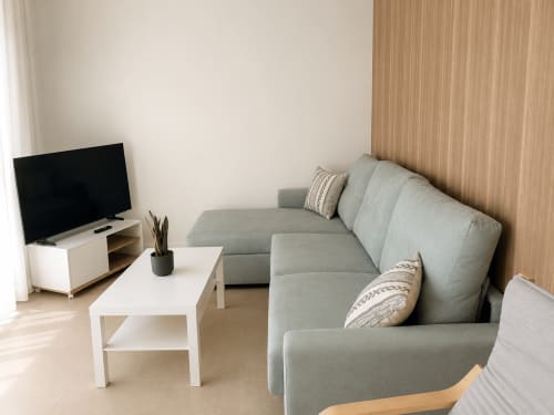 Moderno salón con sofá gris, mesa de café blanca y TV en apartamento Sabaris cerca de Playa Ladeira
