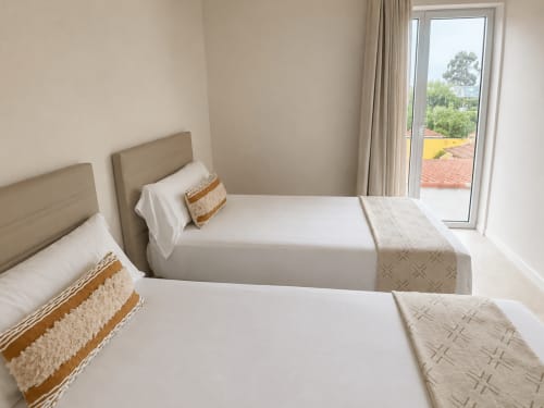 Camas gemelas con cabeceros beige y caminos estampados en la luminosa habitación de Holibai cerca de Playa Ladeira, Sabarís