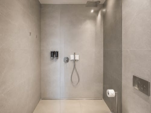 Baño moderno con ducha de azulejos beige, alcachofa de lluvia y accesorios cromados en el apartamento Holibai en Sabaris