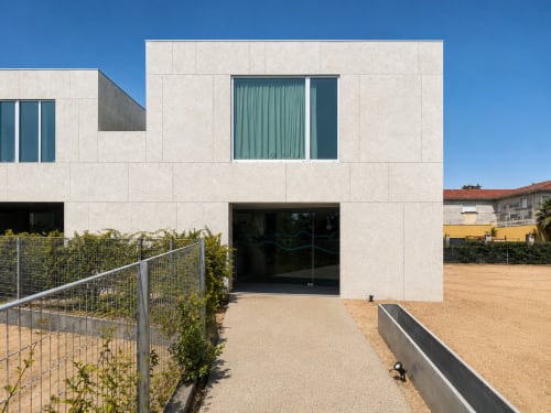 Moderno edificio blanco con terraza, amplios ventanales, valla metálica y jardín arenoso cerca de Playa Ladeira en Sabarís.