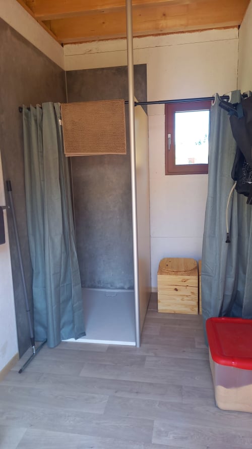 Intérieur de la Yourte TAKHI à La Yourte Un Autre Monde au Hohwald, avec cabine de douche à rideaux et bois