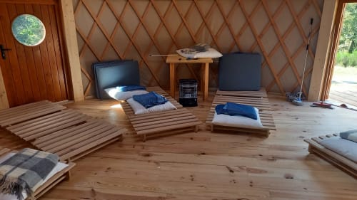 Chambre Yourte TAKHI à La Yourte Un Autre Monde au Hohwald avec lits en bois, coussins bleus et vue sur les montagnes