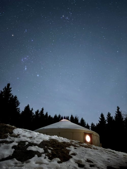 Yourte illuminée sous un ciel étoilé enneigé avec forêt de sapins, constellation d'Orion visible, Le Hohwald