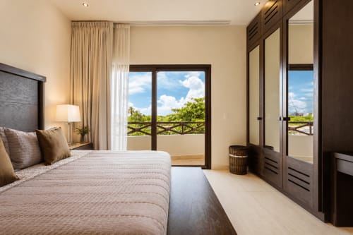 Oceanfront bedroom at Casa Javi in Isla Mujeres with sea view balcony, dark wood furnishings, and tropical landscape.