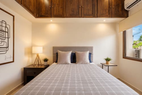 Modern bedroomwith ocean view at Casa Javi, Isla Mujeres. Queen bed, wood cabinets, nightstand lamp, and balcony access.