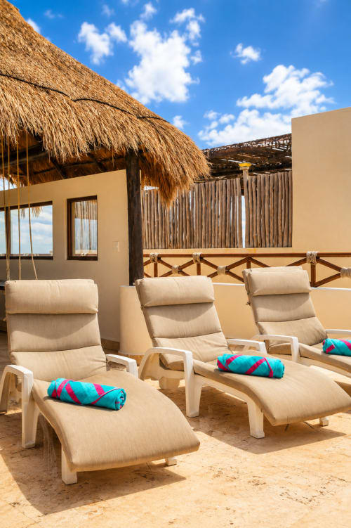 Three lounge chairs with colorful towels on sandy beach at Casa Javi Ocean Front cottage in Isla Mujeres, Mexico, with