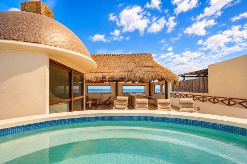 Oceanfront cottage at Casa Javi Isla Mujeres with turquoise pool, thatched roof, sea view seating, and tropical beach access.