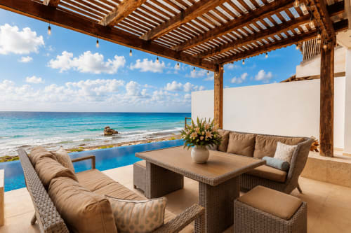 Oceanfront patio at Casa Javi Isla Mujeres with wicker seating, infinity pool, and Caribbean Sea view