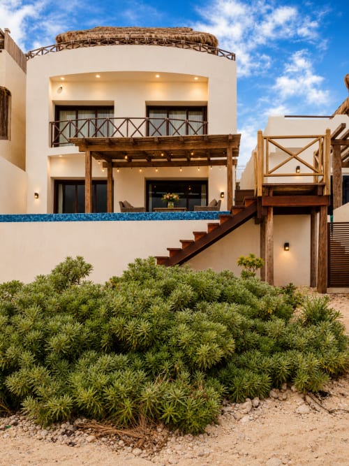 Casa Javi oceanfront cottage in Isla Mujeres with white walls, wooden accents, desert landscaping and blue tile details