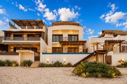 Beachfront cottage with white walls, thatched roofing, and wooden details overlooking the sand in Isla Mujeres, Mexico