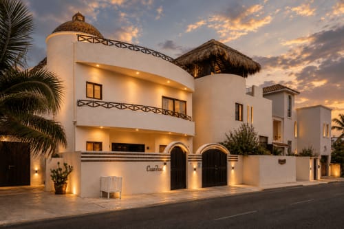 Casa Javi oceanfront cottage in Isla Mujeres with white stucco walls, thatched roof details, and warm evening lighting