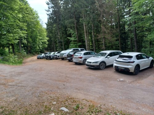 Parking en gravier avec voitures garées entouré de grands arbres forestiers à La Yourte Un Autre Monde, Le Hohwald
