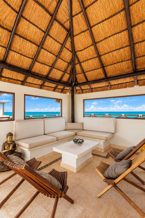 Beachfront living room with thatched ceiling, cream seating, ocean views at Casa Javi, Isla Mujeres